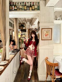 Woman in a red cardigan and plaid skirt posing in a restaurant