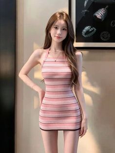 Woman in a pink striped halter dress posing indoors