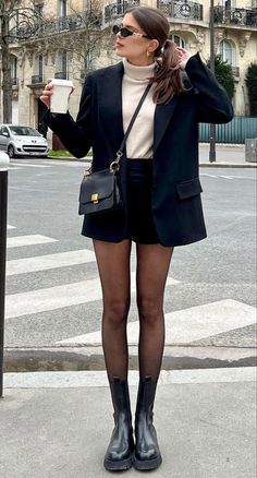 Woman in a black blazer and shorts with a turtleneck sweater on a city street