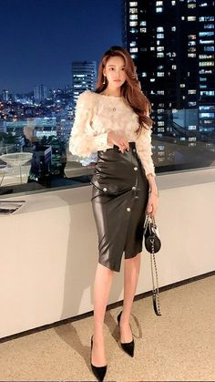 Woman in a white top and black leather skirt with a city night view
