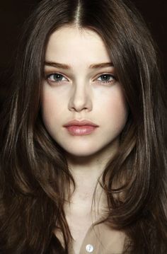 Close-up portrait of a woman with long brown hair and green eyes