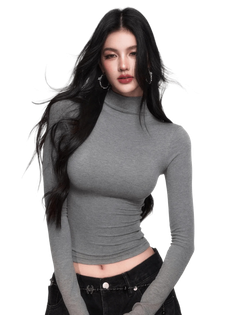 Woman with long black hair wearing a gray turtleneck cropped top and black jeans