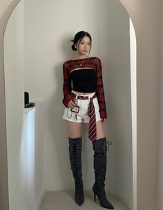 Woman in white shorts and over the knee boots posing indoors