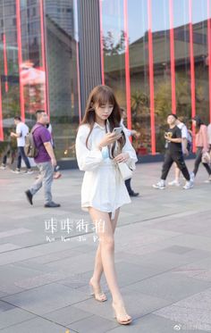 Woman in a white shirt dress and clear heels walking on a city street