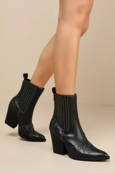 Person wearing black cowboy boots with white stitching and exposed legs