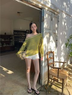 Woman in an off-shoulder sweater and white shorts standing outdoors