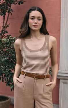 Woman with long hair wearing a striped tank top and tan pants outdoors