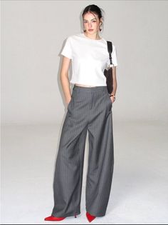 Woman in a white t-shirt and pinstripe pants with red heels in a studio