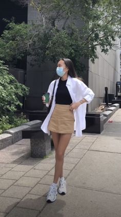 Woman in a white shirt, black top, and mini skirt walking outdoors