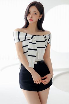 Woman in a striped off-shoulder top and black shorts indoors