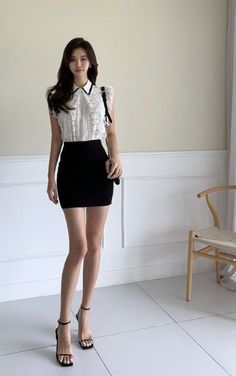 Woman in a white lace top and black mini skirt posing indoors