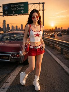 Woman in a red crop top and mini skirt standing on a highway at sunset