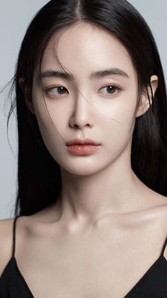 Woman with long black hair wearing a black top, looking to the side