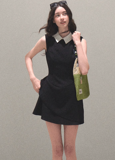 Woman in a black dress with a white collar and a green bag