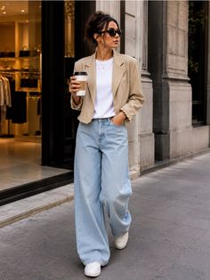 Woman in wide leg jeans and a cropped blazer walking on a city street