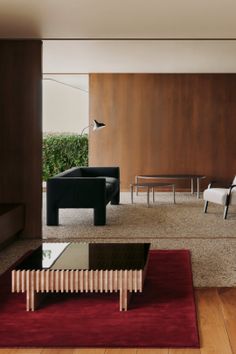 Modern living room with a black sofa, wooden coffee table, and red rug