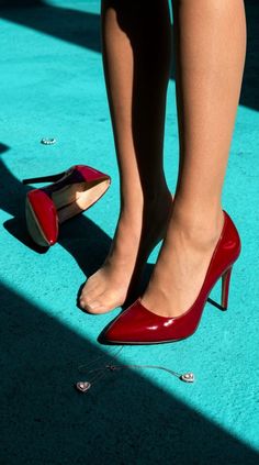 Woman's legs in nude stockings and red high heels on a turquoise floor