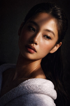 Woman in a white bathrobe with dramatic lighting on her face