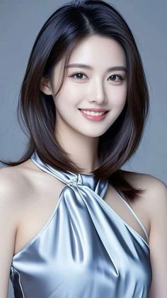 Woman with black hair wearing a silver halter top, smiling at the camera