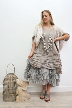 Woman in a layered neutral-colored dress with a long bobble necklace