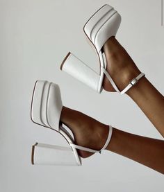 Two feet wearing white platform block heel shoes with ankle straps