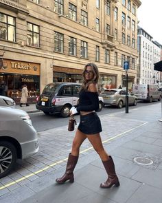 Woman in a black mini skirt and knee high boots walking on a city street