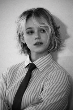 Woman with short blonde hair wearing a striped shirt and tie