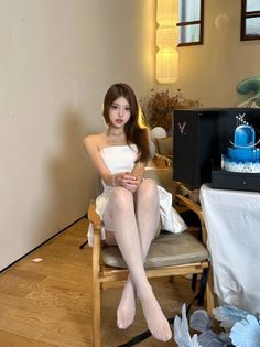Woman in a white dress and stockings sitting on a chair indoors