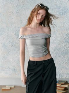 Woman in an off-shoulder top and black pants with sunglasses on her head