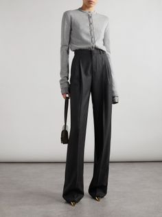 Woman in a grey cardigan and wide leg pants holding a small handbag