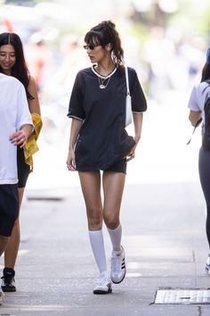 Woman in a black t-shirt dress and white socks walking on a street