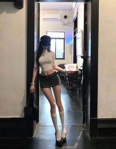 Woman in a crop top and mini skirt with knee-high socks and high heels