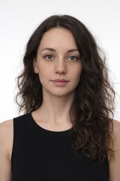 Woman with long wavy dark hair and green eyes wearing a black top