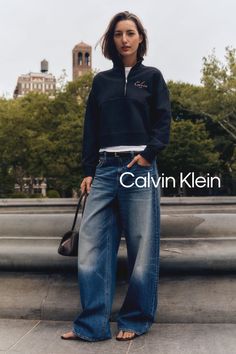 Woman with short hair wearing a dark sweatshirt and wide leg jeans outdoors
