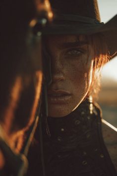 Woman in a cowboy hat with freckles and red hair in golden hour light