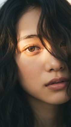 Close up of a woman's face with dark wavy hair and golden hour lighting