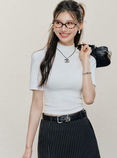 Woman with long hair and glasses wearing a white top and striped skirt