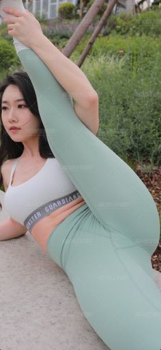Woman in a mint green leggings and sports bra doing a yoga pose outdoors