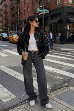 Woman in a black leather jacket and wide leg jeans on a city street