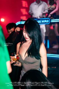 Woman with long dark hair in a nightclub, holding a drink