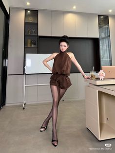 Woman in a brown romper and sheer pantyhose posing indoors