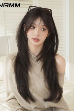 Woman with long dark hair and glasses on her head wearing an off-shoulder top