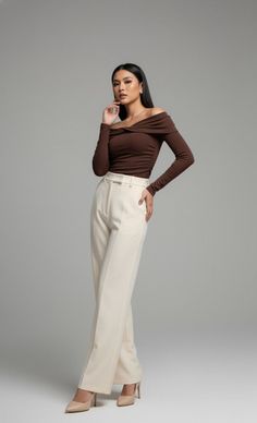 Woman in a brown off-shoulder top and cream high-waisted pants posing in a studio