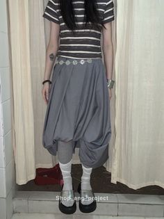 Person in a striped shirt and gray balloon skirt with platform sandals indoors