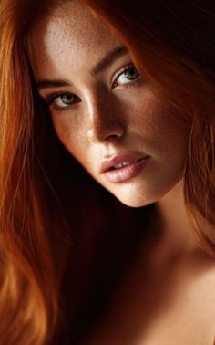 Close up portrait of a woman with red hair, freckles, and green eyes