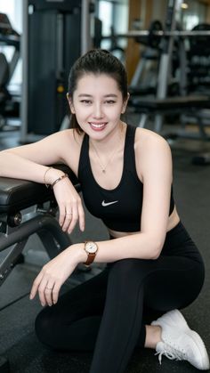 Woman in a black sports bra and leggings smiling in a gym