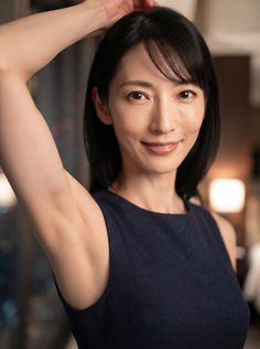 Woman with short dark hair in a dark blue dress, arm raised