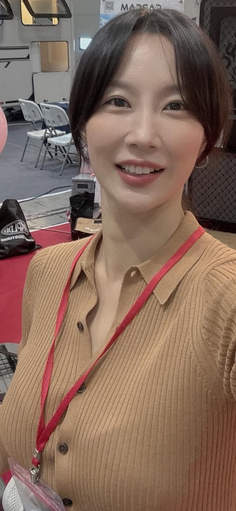Woman with short hair and a red lanyard smiling indoors