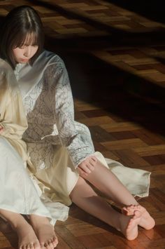 Two people sitting on a wooden floor with soft lighting