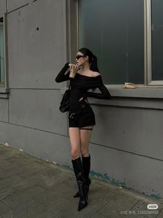 Woman in a black off-shoulder top and shorts with knee-high boots outdoors